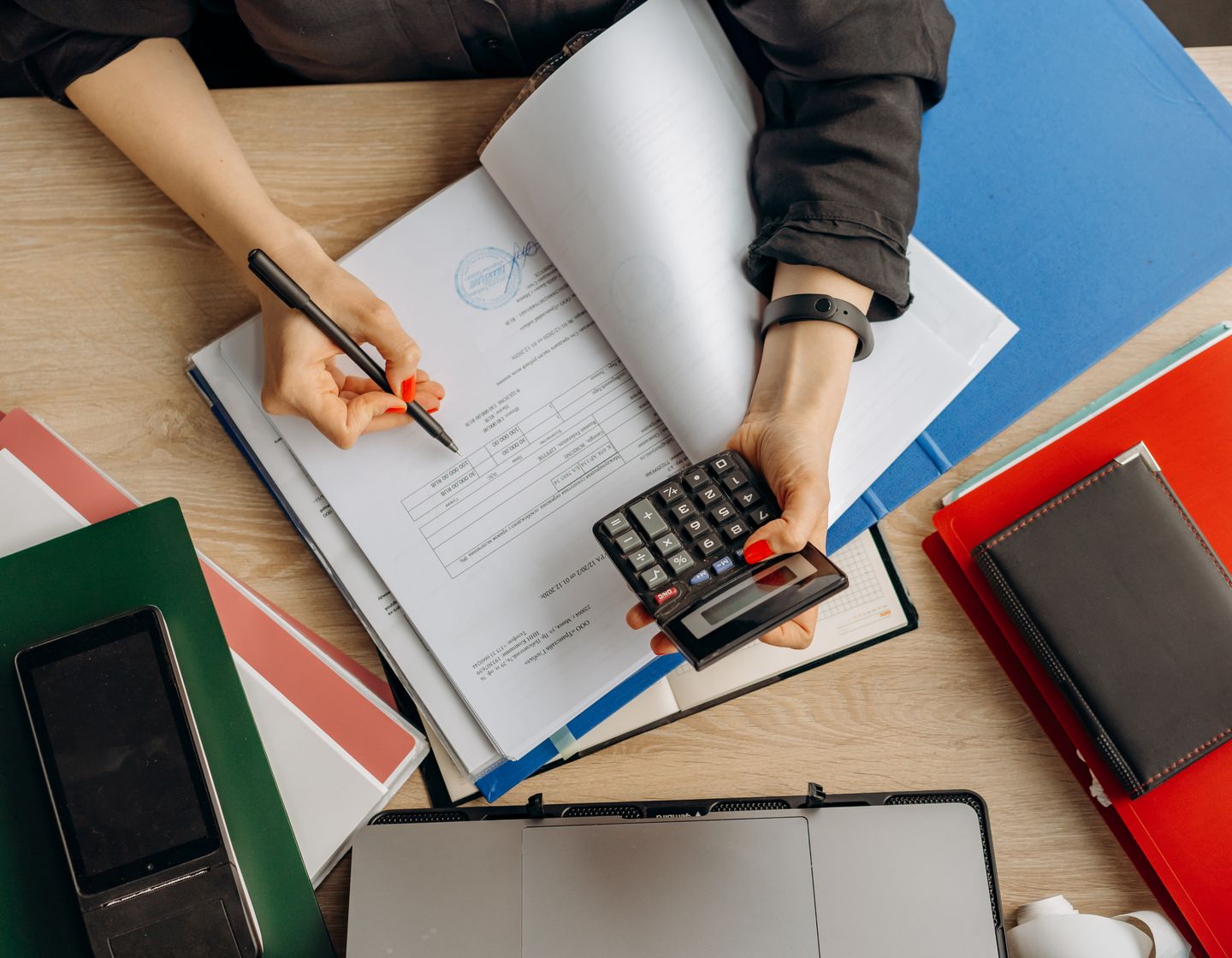 A finance professional checking paperwork with a calculator at a desk