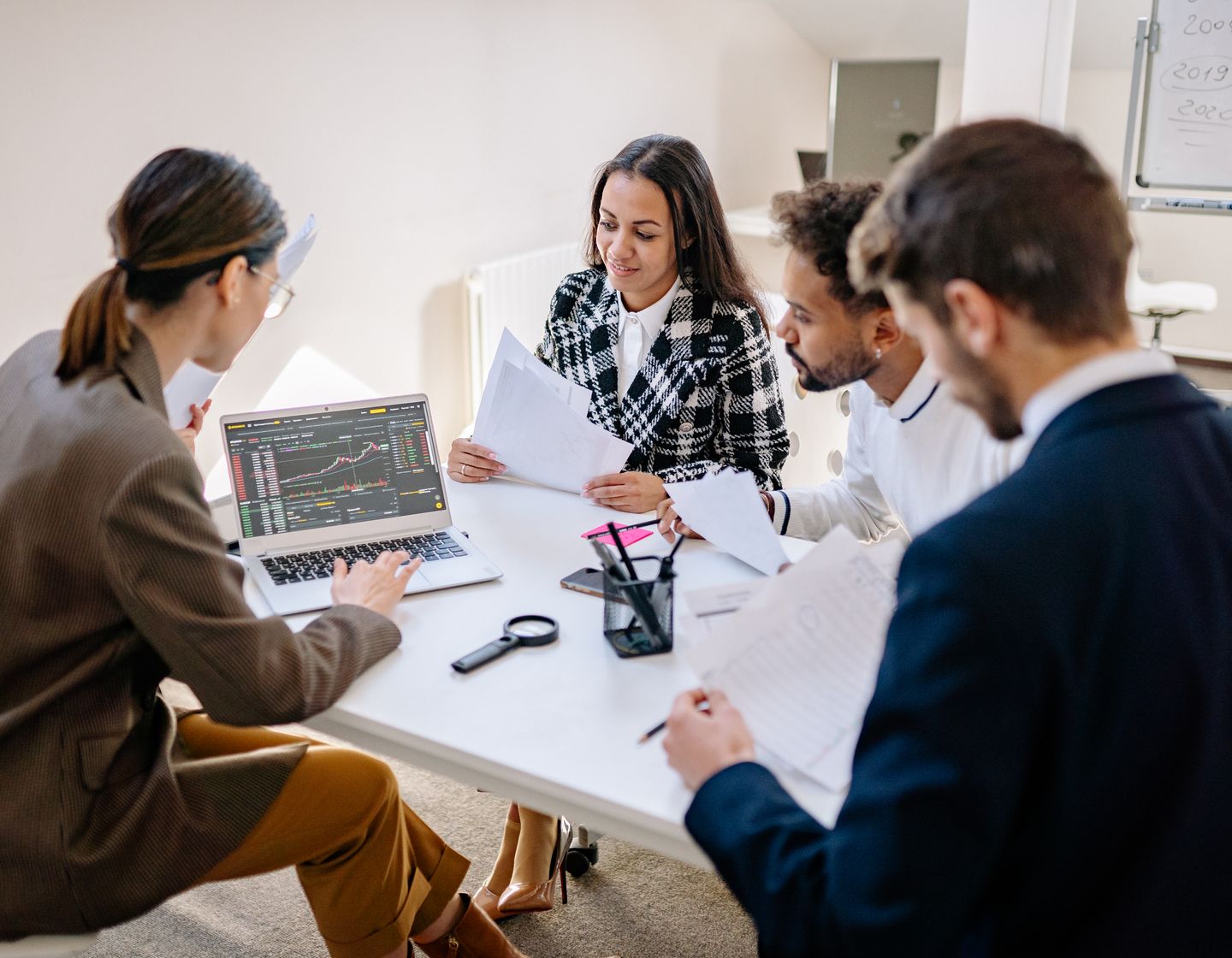 Colleagues working through documents together around an office laptop