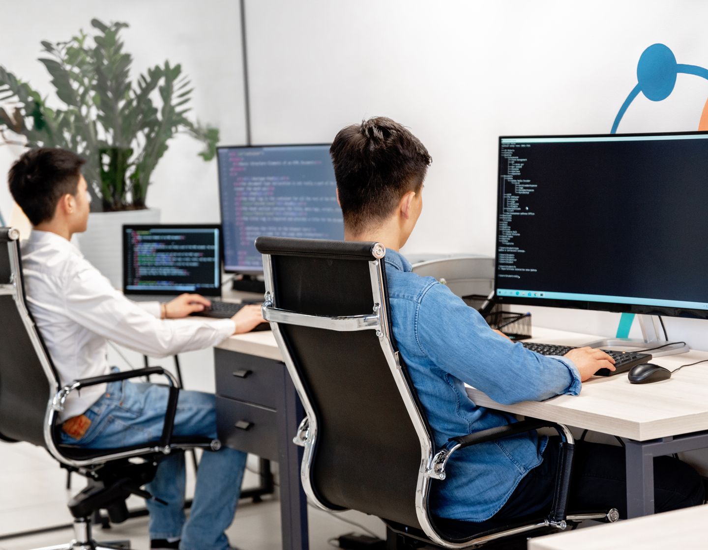 Software developers working at desks with code visible on their monitors